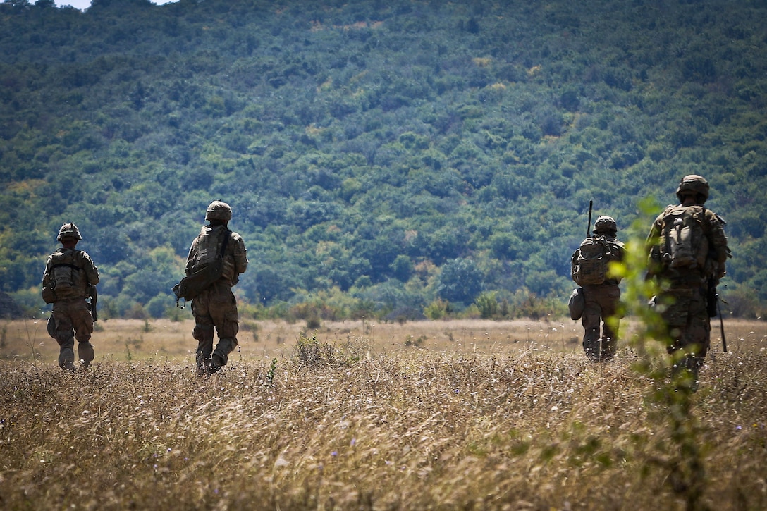 Soldiers maneuver in a tactical formation toward their follow-on objective.