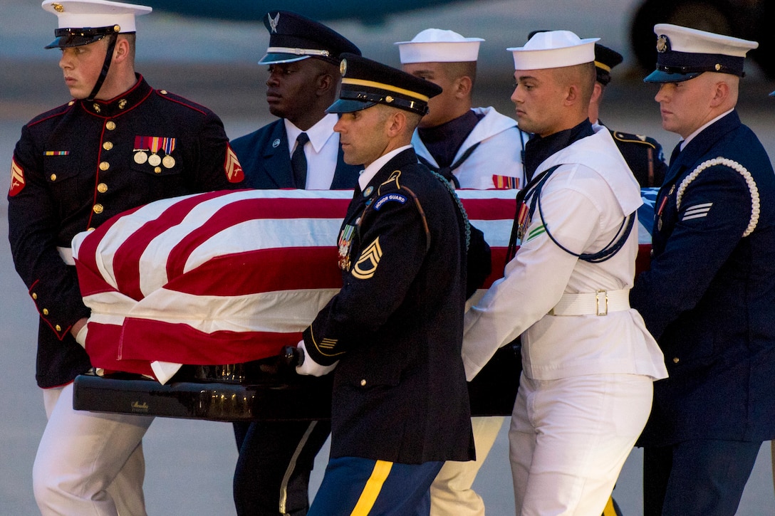 An honor guard carries a flag-draped casket.