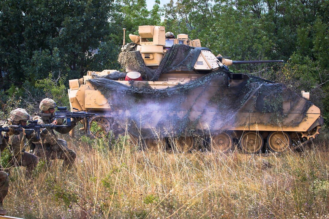 Soldiers fire small arms weapons after dismounting from a M2A3 Bradley fighting vehicle.