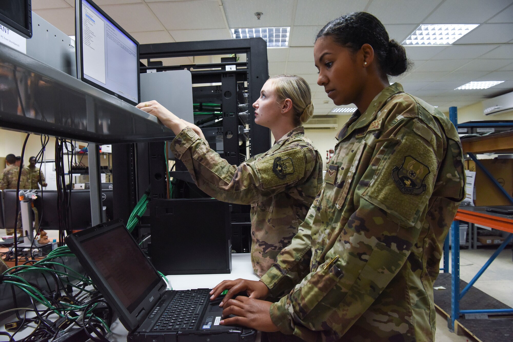 380th Expeditionary Communications Squadron client system technicians Senior Airman Ashley Yarbrough (middle) reimages a computer while Airman 1st Class Angela George (right) installs and updates software on a computer, Nov. 28, 2018 at Al Dhafra Air Base, United Arab Emirates.