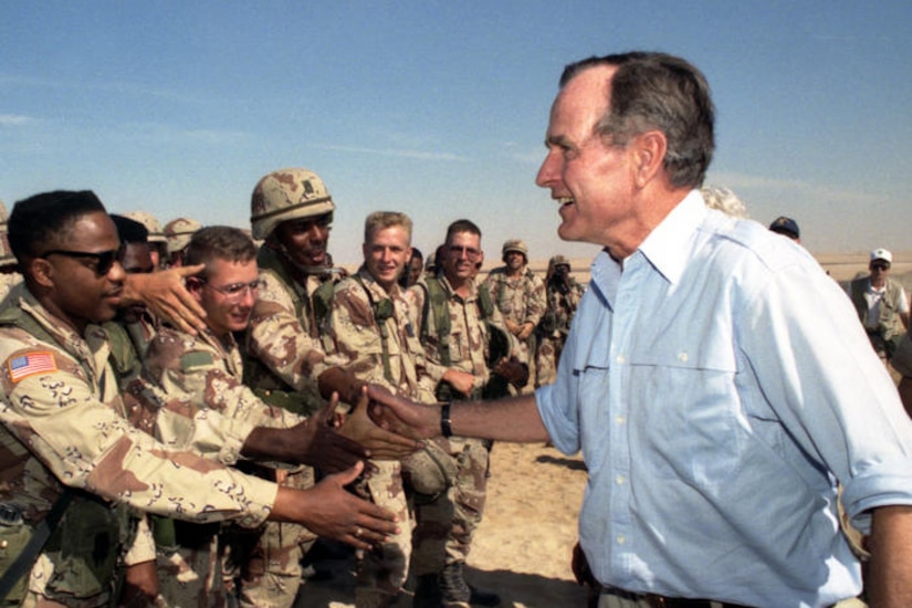 President George H.W. Bush shakes hands with troops.