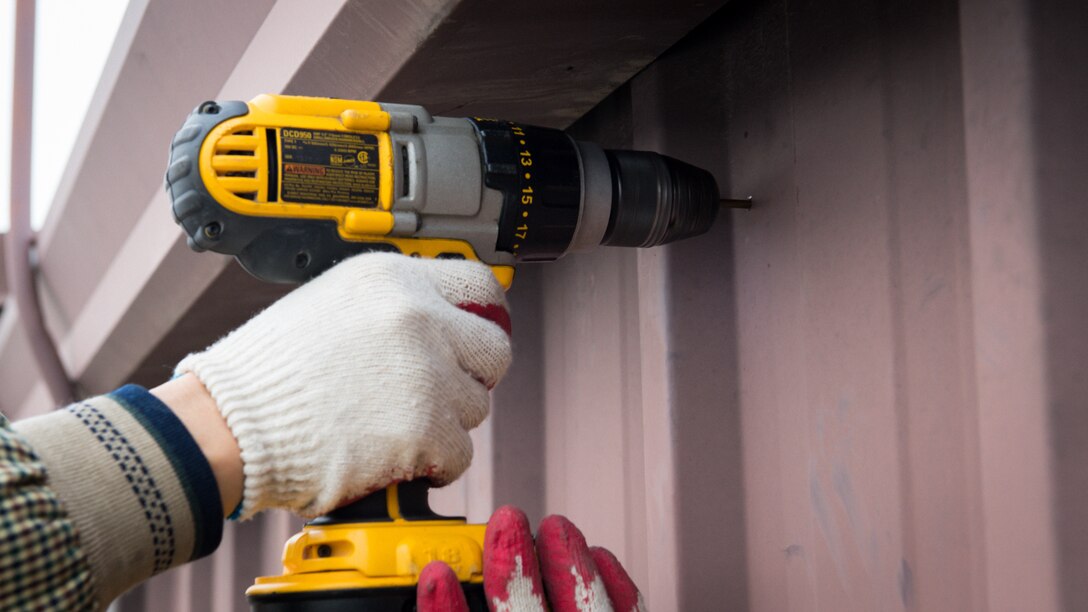 Yong Ui Song, fire alarm technician with the 51st Civil Engineer Squadron, drills a hole into the side of a metal rooftop to secure a new antenna on Osan Air Base, Republic of Korea, Nov. 29, 2018.