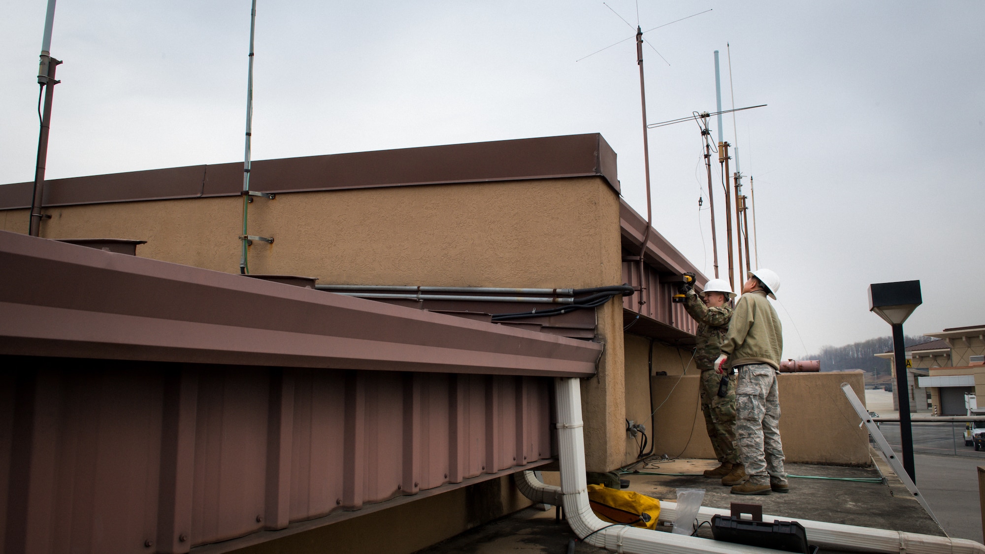U.S. Air Force Airman 1st Class Jesse Slater and Yong Ui Song, fire alarm technicians with the 51st Civil Engineer Squadron, install an AS1 antenna to the roof of the fire department on Osan Air Base, Republic of Korea, Nov. 29, 2018.