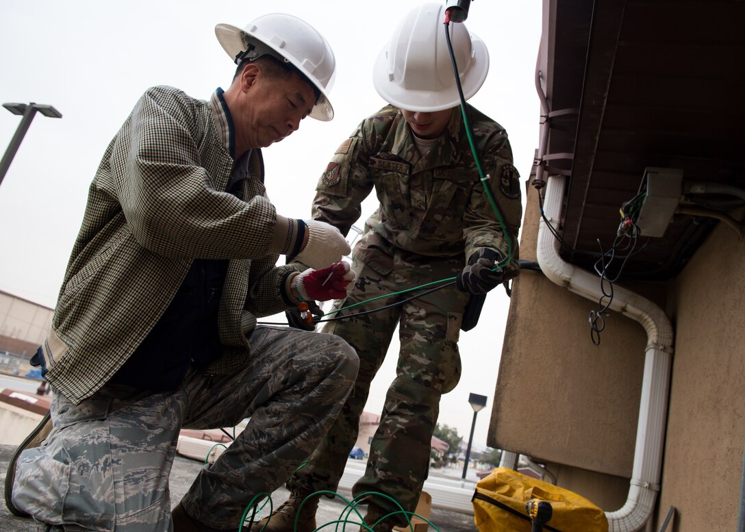 Yong Ui Song, left, and U.S. Air Force Airman 1st Class Jesse Slater, fire alarm technicians with the 51st Civil Engineer Squadron, install a new AS1 antenna on Osan Air Base, Republic of Korea, Nov. 29, 2018.