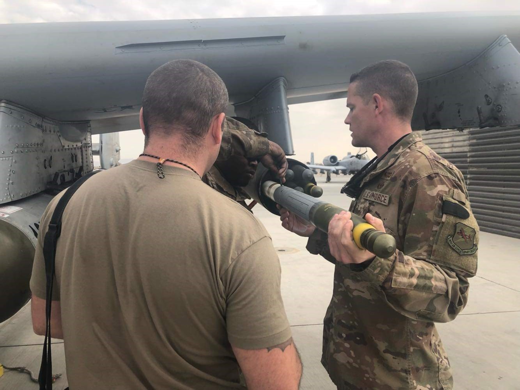 Weapons standardization crew members Staff Sgt. Kyle Palmer (left) and Airman 1st Class Devonta Edmonds (center) teach Maj. Michael Lasher, 451st Expeditionary Aircraft Maintenance Squadron commander, the details about loading AGR-20 rockets at Kandahar Airfield, Afghanistan. (courtesy photo)