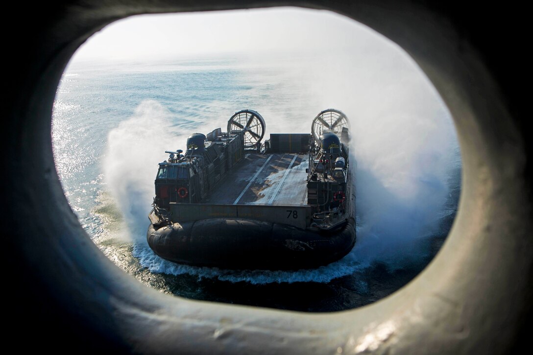 A landing craft air cushion vehicle is seen through a porthole.