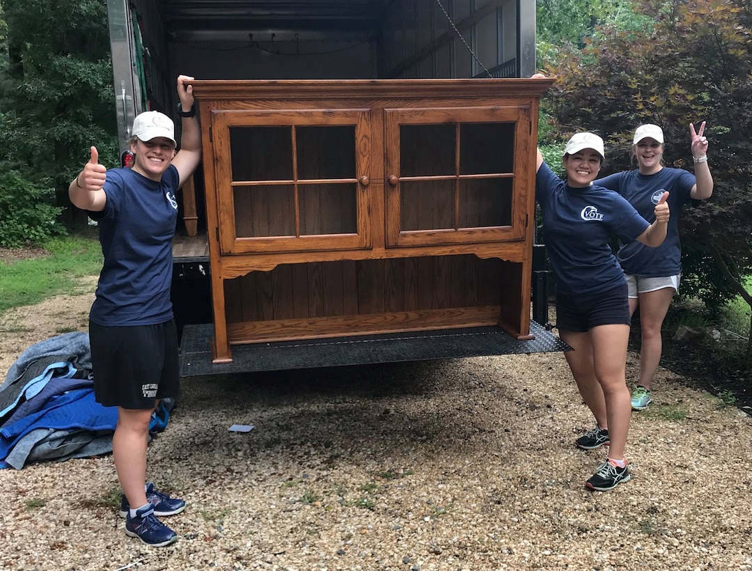 2nd Lt Michelle Burris, center, and two other volunteers with the Vets on Track Foundation take a quick picture while unloading furniture for a veteran who is making the transition from being homeless to a new residence.