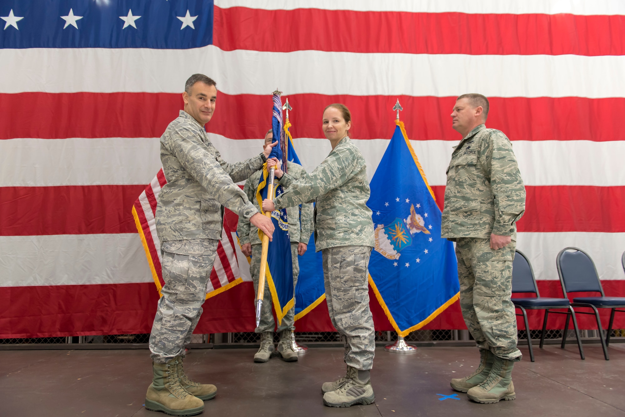 Col. Erik Peterson, the commander of the 115th Fighter Wing, presents the guidon to Lt. Col. Wilhelmina Panzer, the new commander of the 115th Maintenance Group, during the 115 MXG change of command ceremony Dec. 2, 2018, at the 115th Fighter Wing, Truax Field, Wisconsin. Lt. Col. Panzer was previously the inspector general at the 115th Fighter Wing before taking command of the maintenance group.  (U.S. Air National Guard photo by Airman 1st Class Cameron Lewis)