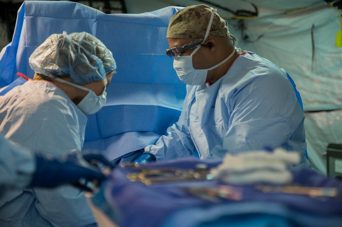 U.S. Navy Lt. Cmdr. Jennifer Ottino, left, and Hospital Corpsman 2nd Class Damian Garcia, right, simulate surgery on a patient during the capabilities display Nov. 27, 2018 at Camp Foster, Okinawa, Japan. Sailors with 3rd Medical Battalion, 3rd Marine Logistics Group, established a Role II capabilities display to give service members the opportunity to view their full facilities. Role II facilities give Sailors the ability to offer ultrasound, X-ray, surgery and dental while providing a place for injured service members to be treated. Ottino, a general surgeon with 3rd Medical Bn., 3rd MLG, is a native of Roseville, California. Garcia, a corpsman with 3rd Medical Bn., 3rd MLG, is a native of Greenacres, Florida. (U.S. Marine Corps photo by Lance Cpl. Mark Fike)