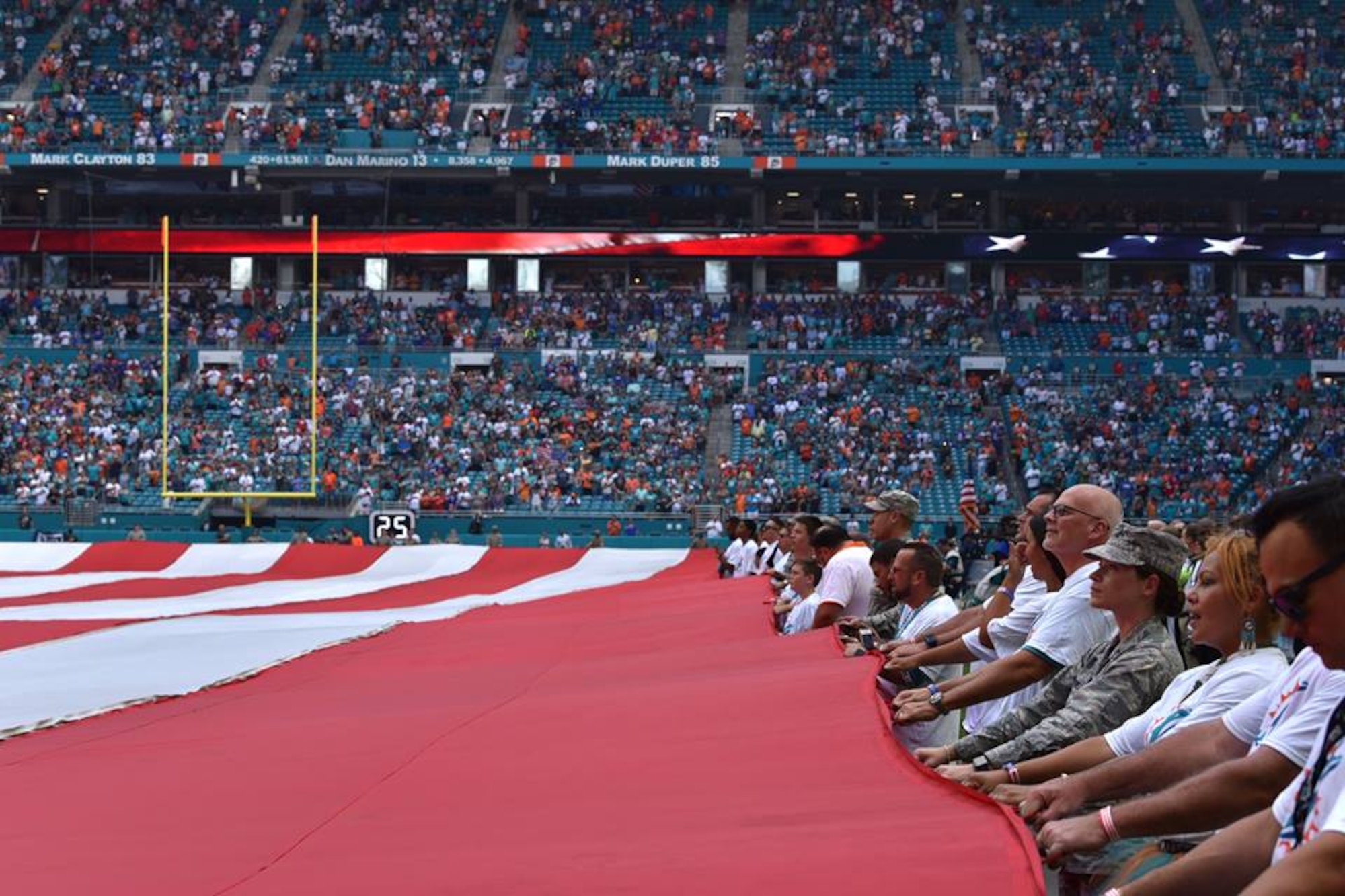 Airmen and local community members unfurl the flag for the National Anthem prior to the start of a Miami Dolphins football game on Dec 2, 2018 in Miami. Approximately 75 Airmen from Patrick Air Force Base, Fla. participated in the event. (U.S. Air Force photo by Tech. Sgt. Andrew Satran)