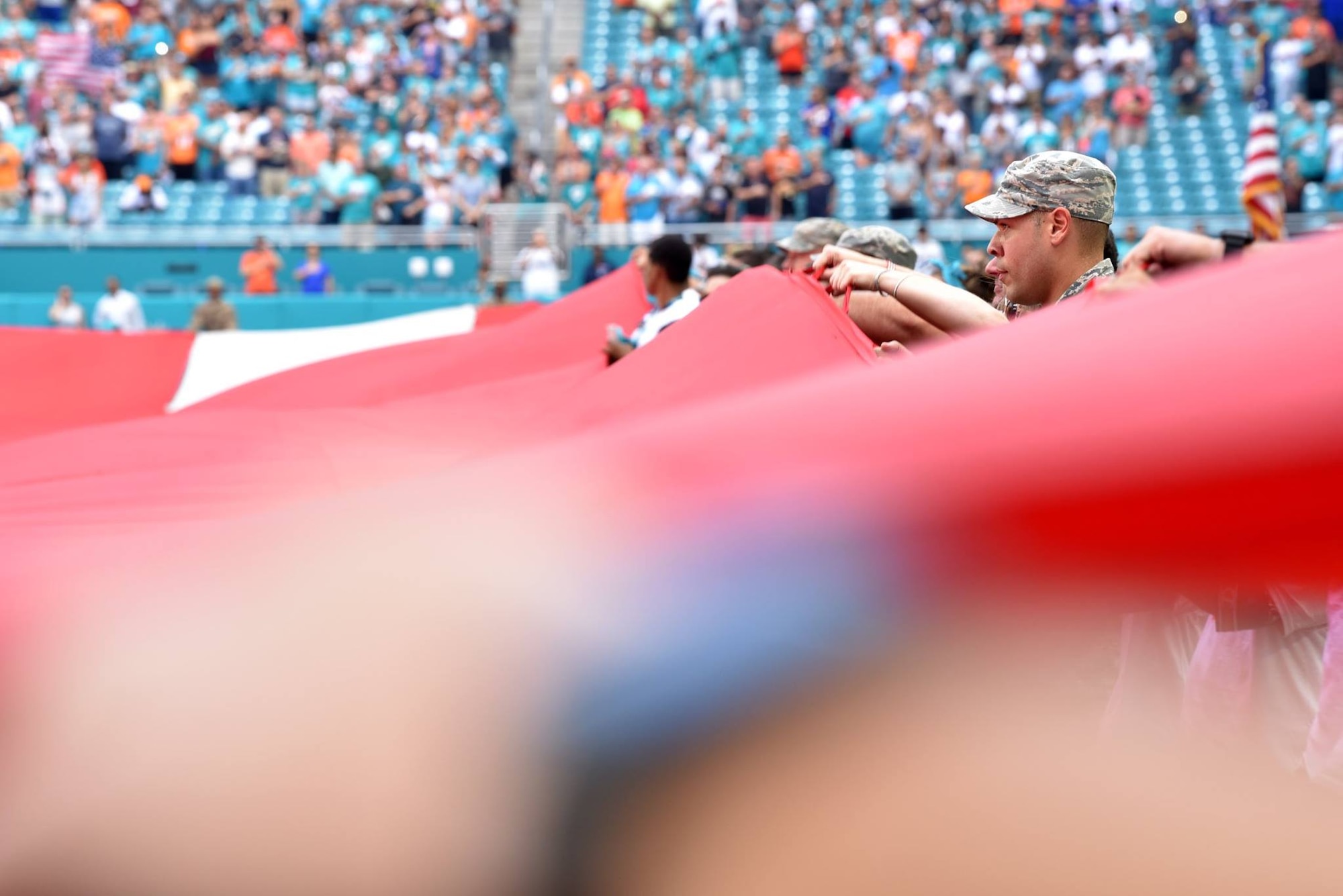 Airmen and local community members unfurl the flag for the National Anthem prior to the start of a Miami Dolphins football game on Dec 2, 2018 in Miami. Approximately 75 Airmen from Patrick Air Force Base, Fla. participated in the event. (U.S. Air Force photo by Tech. Sgt. Andrew Satran)