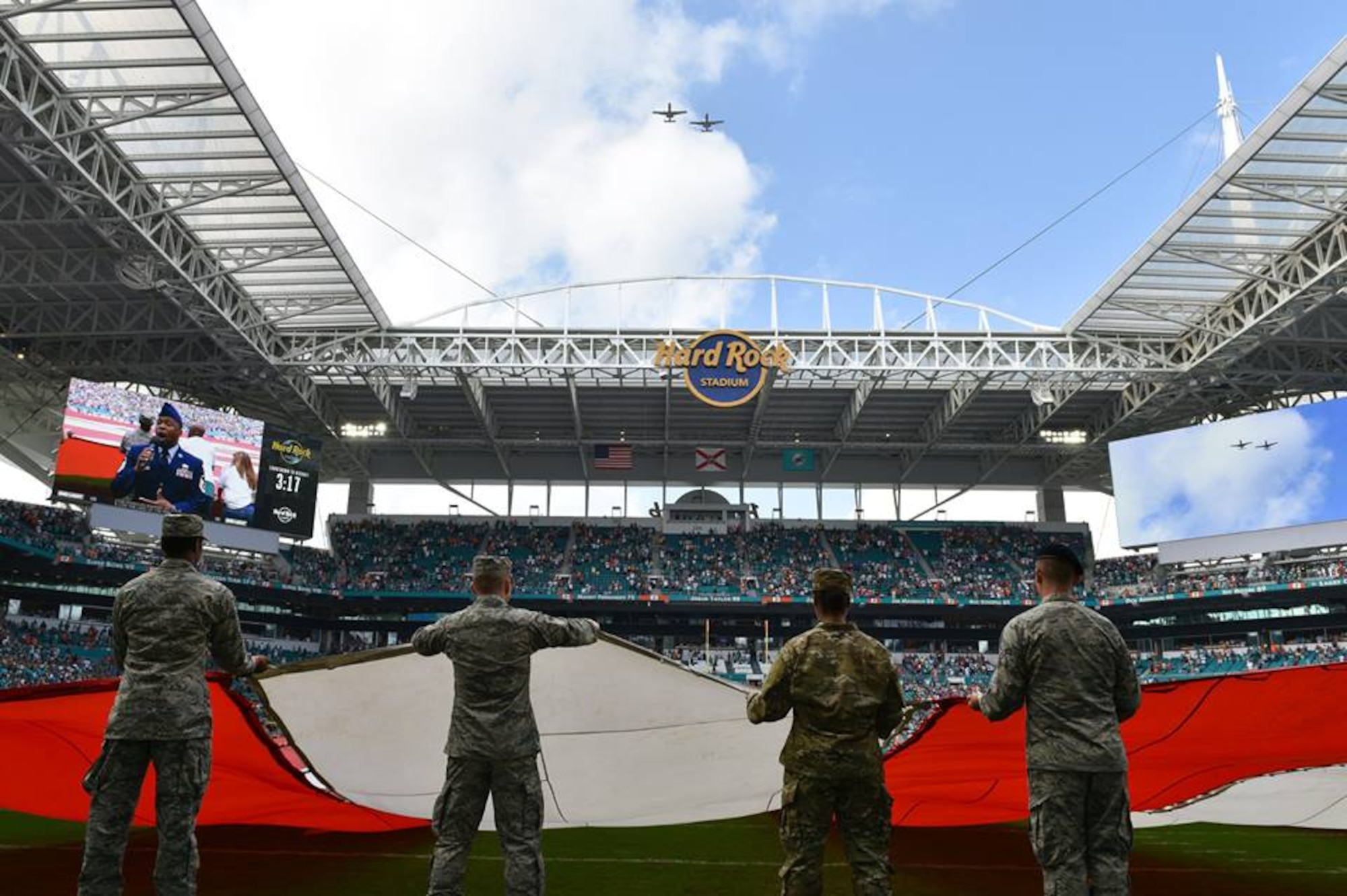 Airmen and local community members unfurl the flag for the National Anthem prior to the start of a Miami Dolphins football game on Dec 2, 2018 in Miami. Approximately 75 Airmen from Patrick Air Force Base, Fla. participated in the event. (U.S. Air Force photo by Tech. Sgt. Andrew Satran)