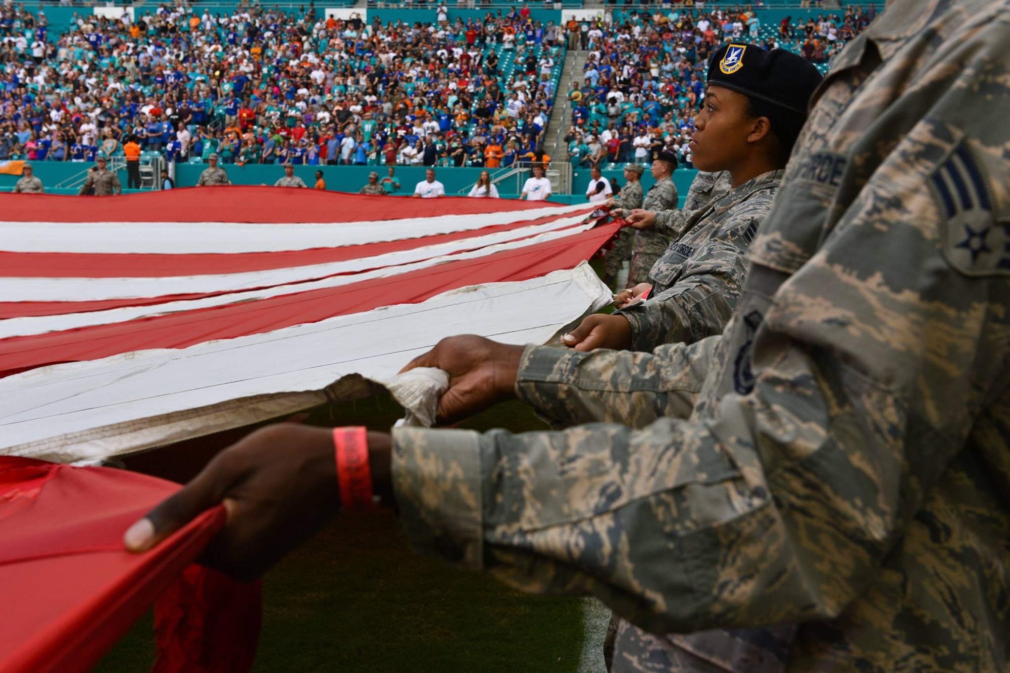 Airmen and local community members unfurl the flag for the National Anthem prior to the start of a Miami Dolphins football game on Dec 2, 2018 in Miami. Approximately 75 Airmen from Patrick Air Force Base, Fla. participated in the event. (U.S. Air Force photo by Airman 1st Class Dalton Williams)