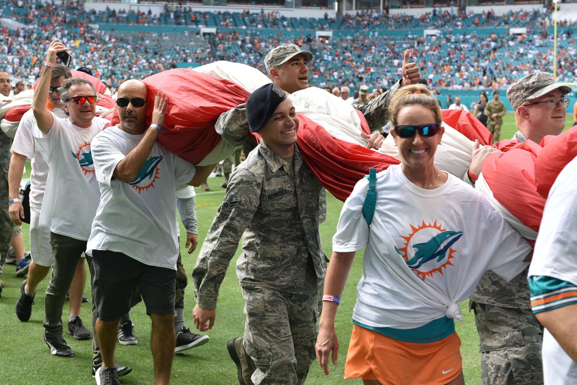 Airmen and local community members unfurl the flag for the National Anthem prior to the start of a Miami Dolphins football game on Dec 2, 2018 in Miami. Approximately 75 Airmen from Patrick Air Force Base, Fla. participated in the event. (U.S. Air Force photo by Airman 1st Class Dalton Williams)