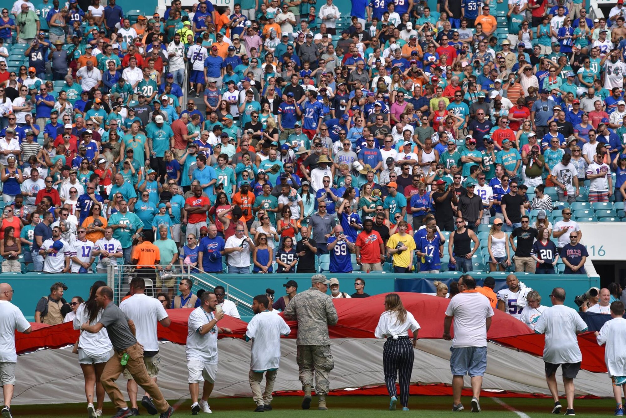 Airmen and local community members unfurl the flag for the National Anthem prior to the start of a Miami Dolphins football game on Dec 2, 2018 in Miami. Approximately 75 Airmen from Patrick Air Force Base, Fla. participated in the event. (U.S. Air Force photo by Tech. Sgt. Andrew Satran)