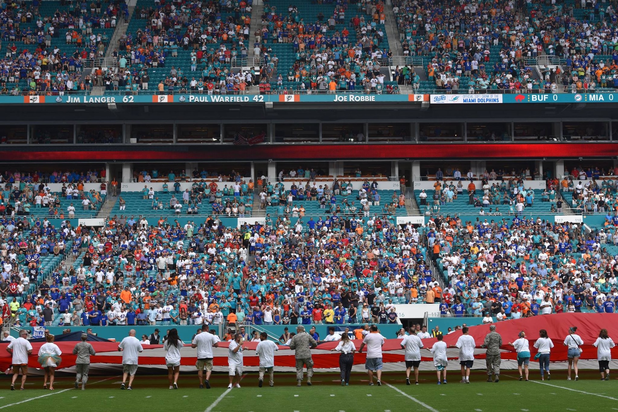 Airmen and local community members unfurl the flag for the National Anthem prior to the start of a Miami Dolphins football game on Dec 2, 2018 in Miami. Approximately 75 Airmen from Patrick Air Force Base, Fla. participated in the event. (U.S. Air Force photo by Tech. Sgt. Andrew Satran)