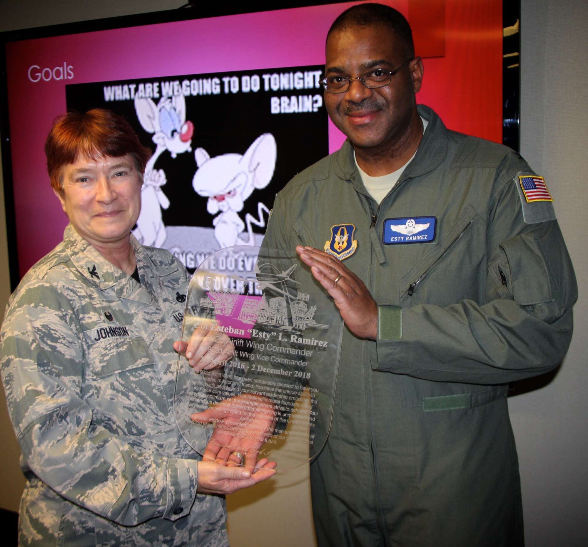 Commander of the 932nd Maintenance Group, Col. Sharon Johnson, presents a farewell gift to outgoing vice commander, Col. Esty Ramirez during his final staff meeting on Nov. 30, 2018, at Scott Air Force Base, Ill.  Part of the inscription reads, "The 932nd Airlift Wing has been remarkably blessed to have you as leader, mentor and friend.  You have the unique ability to connect with people and your servant leadership embodies the Air Force core values."  (U.S. Air Force photo by Lt. Col. Stan Paregien)