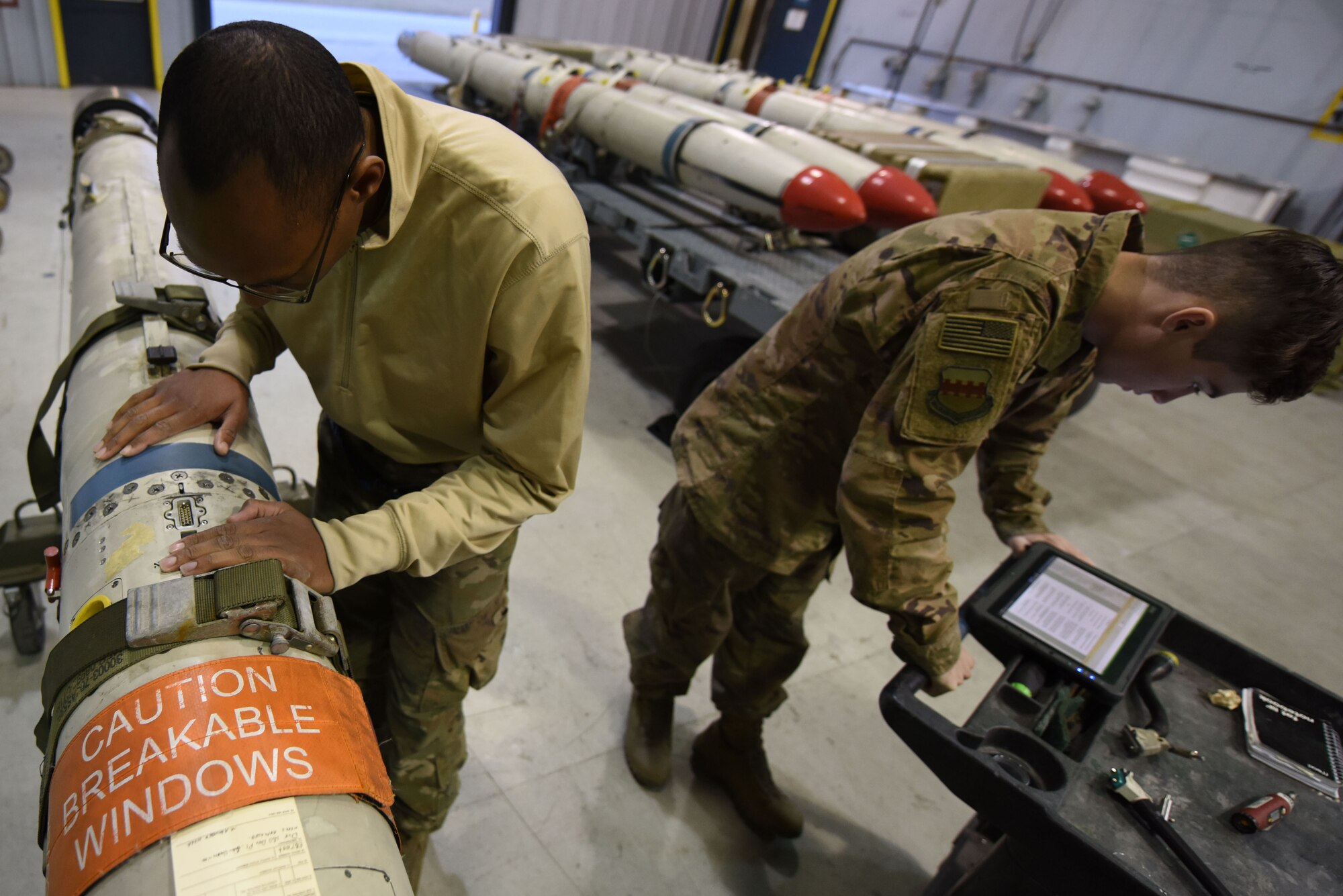 U.S. Air Force Senior Airman Larry Wallace, left, and Senior Airman Allen Jenlink, right, 20th Equipment Maintenance Squadron precision guidance munitions crew chiefs, work together to replace a cable on an AGM-88 missile at Shaw Air Force Base, S.C., Nov. 30, 2018.