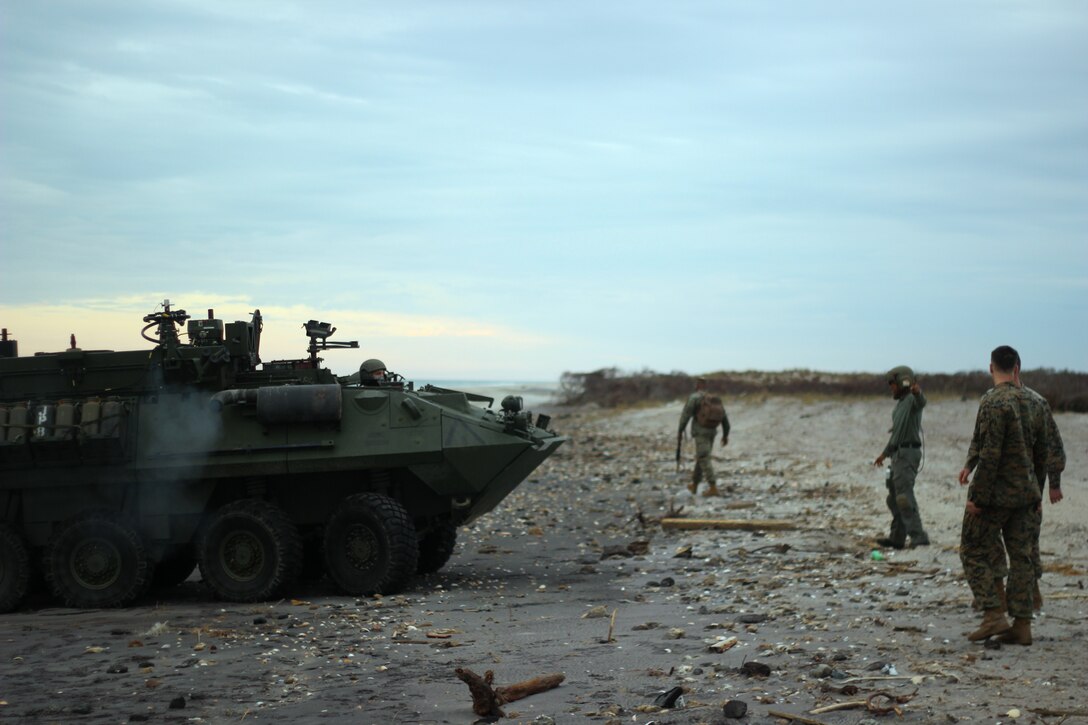 A U.S. Marine guides a light armored vehicle with the 2nd Light Armored Reconnaissance Battalion onto Onslow Beach at Camp Lejeune, North Carolina, Nov. 30, 2018. Marines and Sailors with the 24th Marine Expeditionary Unit participated in Exercise Trident Juncture in Norway and Iceland and returned home from USS New York (LPD 21). (U.S. Marine Corps photo by Gunnery Sgt. Robert Durham)