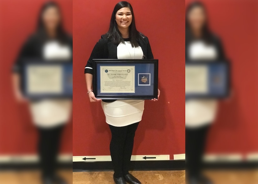 A woman holds a framed award certificate.