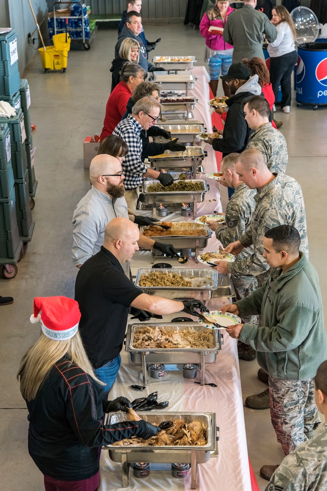 Volunteers help serve Team Dover members as they go through the serving line during the 14th Annual “Feed the Troops” day shift dinner sitting Dec. 19, 2017, in Hangar 792 on Dover Air Force Base, Del. Thirty turkeys were cooked at the Dover Downs kitchen and transported to the base for day and night shift meal sittings. (U.S. Air Force photo by Roland Balik)