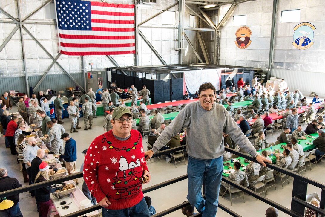 Organizers of the 14th Annual “Feed the Troops” retired Air Force Reserve Technicians Senior Master Sgt. Rene Baldrich, left, and Master Sgt. Robert Reese, right, pose for a photo overlooking the day shift dinner sitting Dec. 19, 2017, in Hangar 792 at Dover Air Force Base, Del. A total of seven hundred-fifty meals were served to Team Dover members by volunteers during the day and night shift meal sittings. Reese held the first “Feed the Troops” in 2004. (U.S. Air Force photo by Roland Balik)