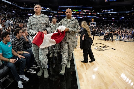 Members of the 59th Medical Wing, Joint Base San Antonio-Lackland, participate in the Living Flag ceremony held before the Dec. 2 game between the San Antonio Spurs and Portland Trailblazers at the AT&T Center in San Antonio, Texas. Nearly 30 Airmen held the flag aloft during the singing of the national anthem. 
(Photo courtesy of the San Antonio Spurs)