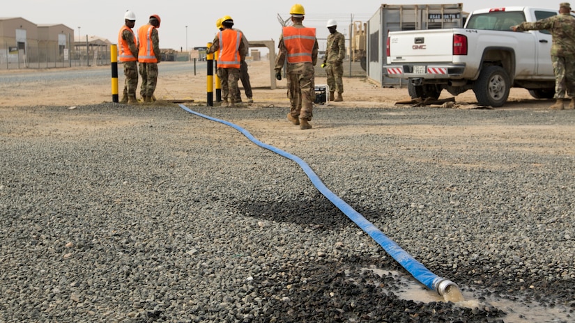 A hose discharges water being pumped from a flooded access service point by a team of Soldiers from U.S. Army Network Enterprise Center-Kuwait, at Camp Buehring, Kuwait, Dec. 1, 2018. Kuwait has experienced unusually heavy rainfall and flooding this past month, and U.S. Army Soldiers have risen to the challenge to remain operational despite the weather challenges.