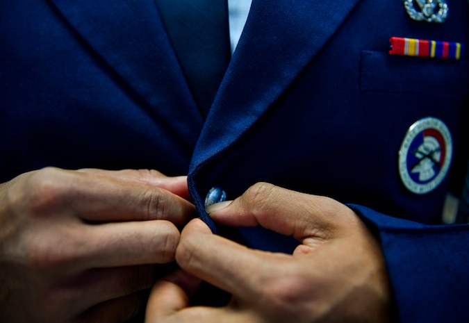 Airman 1st Miguel Alano, 628th Civil Engineer Squadron engineer assistant honor guardsman, buttons his uniform before going to a funeral detail Nov. 30, 2018, at Joint Base Charleston, S.C. The JB Charleston honor guard flight performed an active duty funeral detail, which requires 20 guardsmen as well as extensive training and preparation.