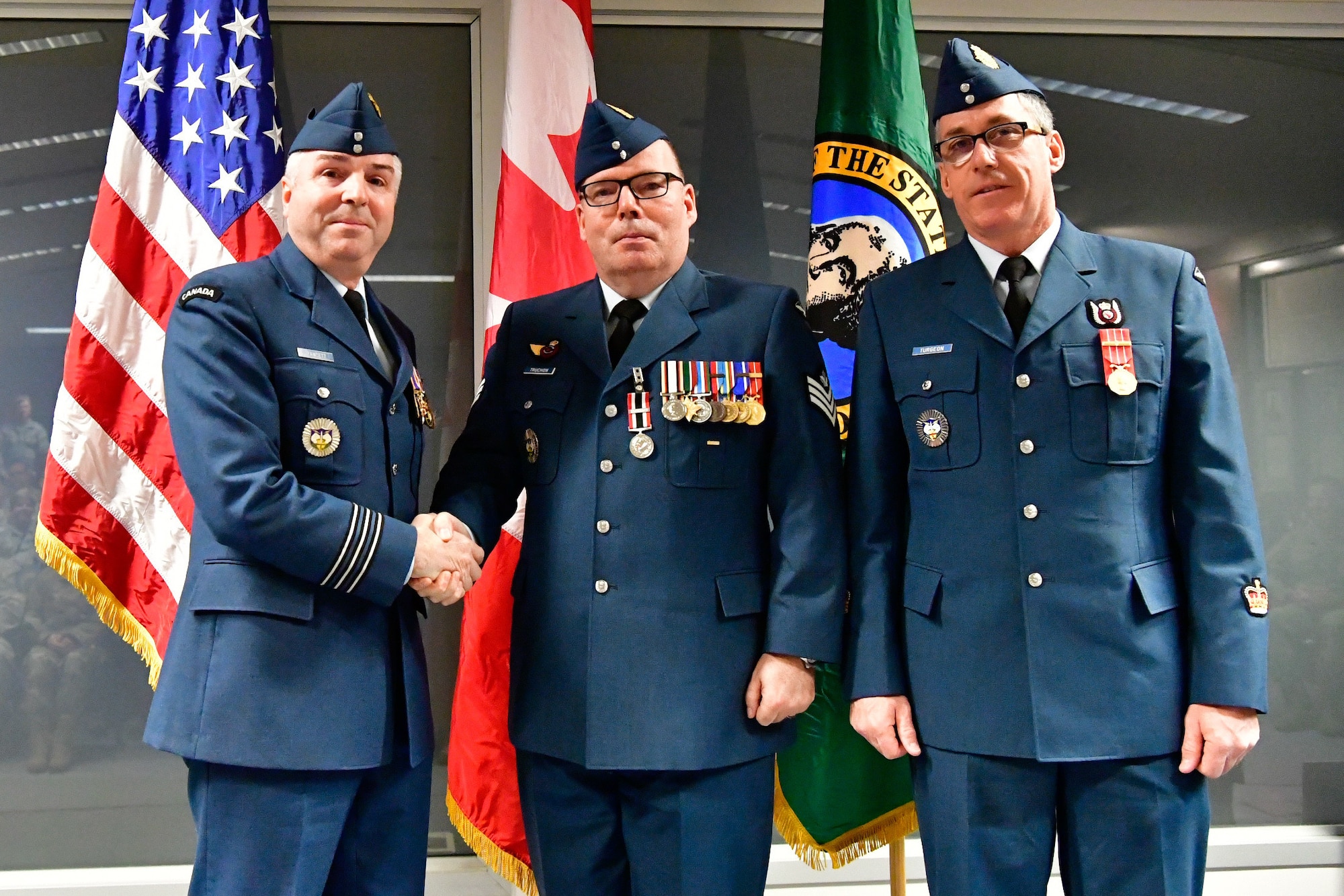 Royal Canadian Air Force Sgt. Yves Truchon (center), Western Air Defense Sector Canadian Detachment command and control battle manager, is awarded the Canadian Armed Forces Special Service Medal with NATO bar from Lt. Col. Michael Fawcett, WADS Canadian Detachment commander (left), Dec. 1, 2018 at Joint Base Lewis-McChord, Washington.  The medal was awarded for Truchon’s exceptional service conducting operations as part of Task Force 2011 (409th Fighter Squadron) and Task Force 2013 (425th Fighter Squadron) during Operation Ignition, the RCAF contribution to the NATO air policing mission over Iceland, providing airborne surveillance and interception capabilities to meet Iceland’s peacetime preparedness needs. The Special Service Medal was created to recognize members of the Canadian Armed Forces who have performed a service determined to be under exceptional circumstances, in a clearly defined locality for a specified duration.  The SSM is always issued with a bar that specifies the special service being recognized, each bar having its own criteria. (U.S. Air National Guard photo by Maj. Kimberly D. Burke)