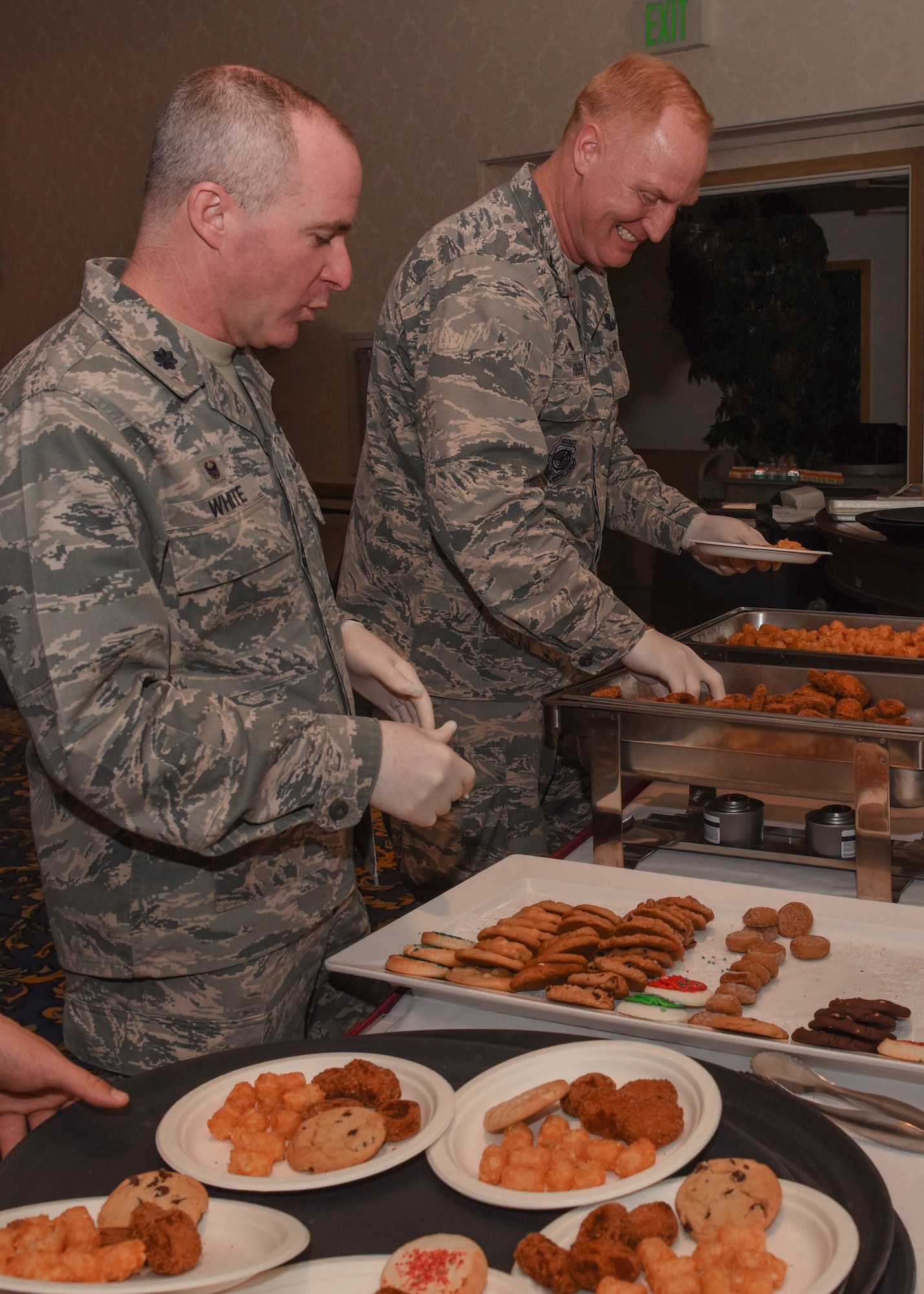 Col. Michael Hough, 30th Space Wing commander, and Lt. Col. Ryan White, Space Communication Squadron commander, prepare plates for the children at Operation Kids Christmas at the Pacific Coast Club at Vandenberg Air Force Base, Calif. Dec. 1, 2018. Vandenberg hosts the 59th annual Operation Kids Christmas here, expecting 200 kids from nearby cities to partake in the planned games, crafts, lunch and Christmas gifts.