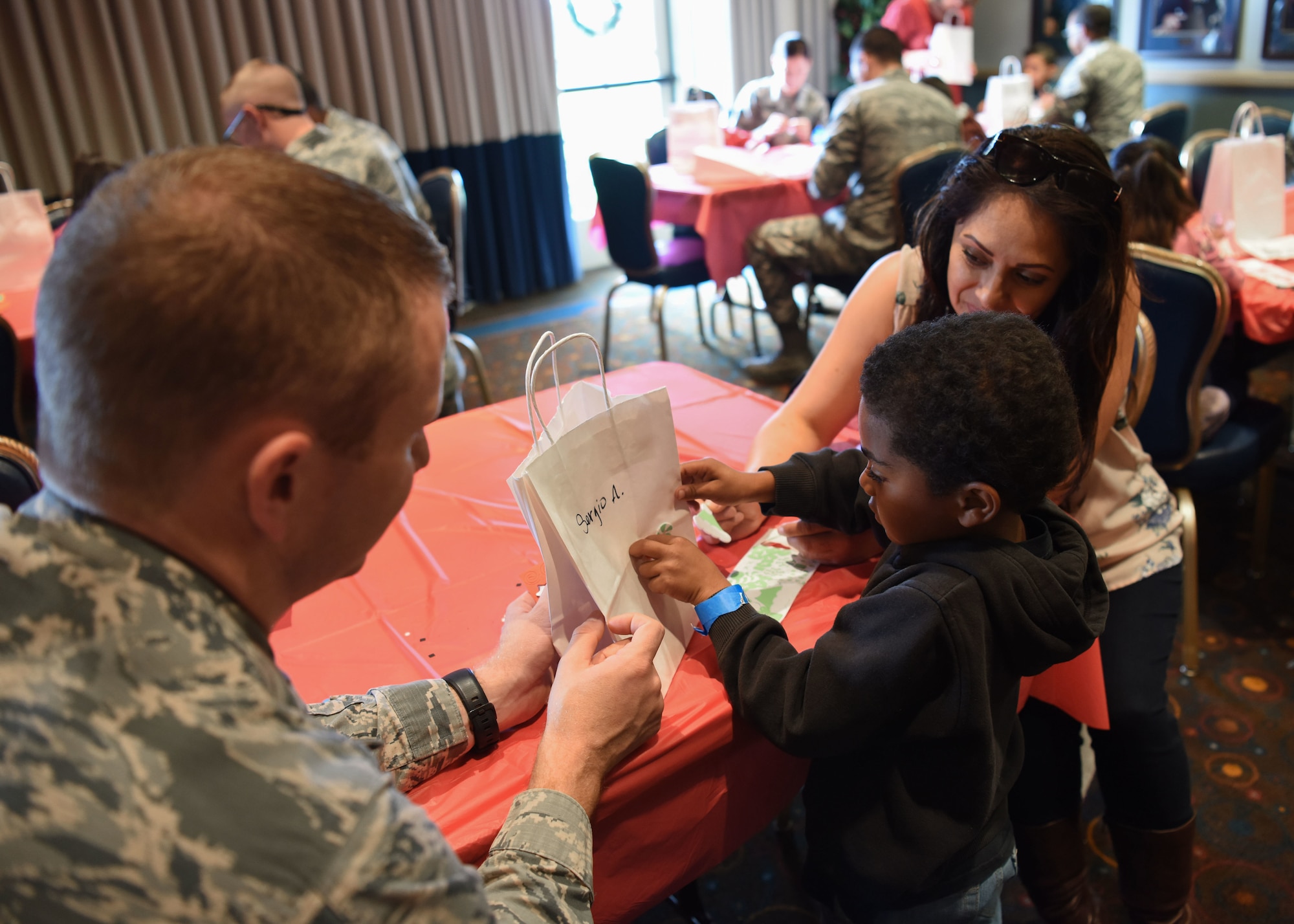 Maj. Kenneth Peters, 30th Space Wing Comptroller Squadron commander, assists his assigned child during crafts at Operation Kids Christmas at the Pacific Coast Club at Vandenberg Air Force Base, Calif. Dec. 1, 2018. Vandenberg hosts the 59th annual Operation Kids Christmas here, expecting 200 kids from nearby cities to partake in the planned games, crafts, lunch and Christmas gifts.
