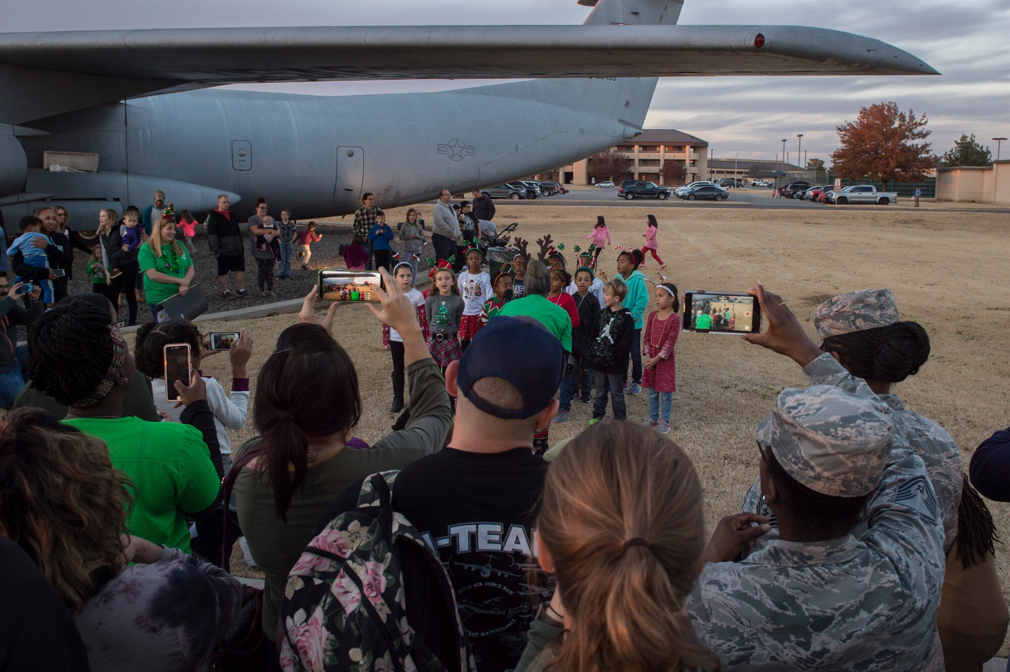 Members of the 97th Air Mobility Wing record videos of their children performing various holiday songs, Nov. 29, 2018, at Altus Air Force Base, Okla. Every year children of the 97th Air Mobility Wing perform songs for the holiday tree lighting event. (U.S. Air Force photo by Senior Airman Cody Dowell)