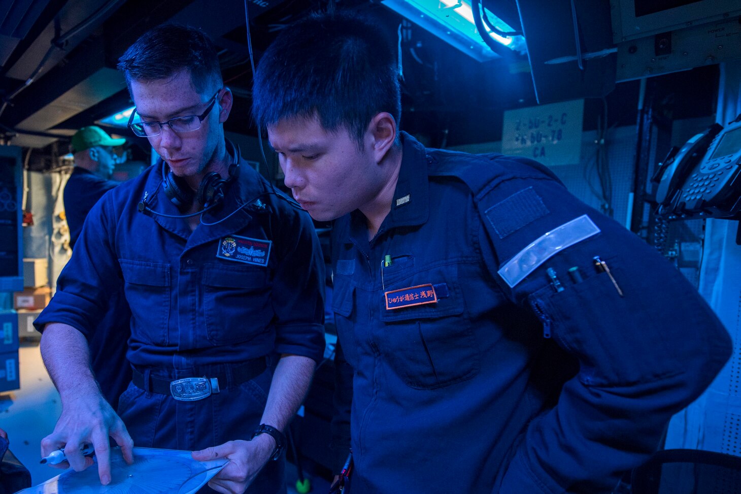WATERS SOUTH OF JAPAN (Dec. 4, 2018) Sonar Technician (Surface) 2nd Class Joseph Hines, from Denver, explains how to use a range finder to Japan Maritime Self-Defense Force (JMSDF) Ensign Asano Shinchi, assigned to the JMSDF destroyer JS Hyuga (DDH-181), in the sonar control room aboard the Arleigh Burke-class guided-missile destroyer USS Benfold (DDG 65). Benfold is forward-deployed to the U.S. 7th Fleet area of operations in support of security and stability in the Indo-Pacific region.