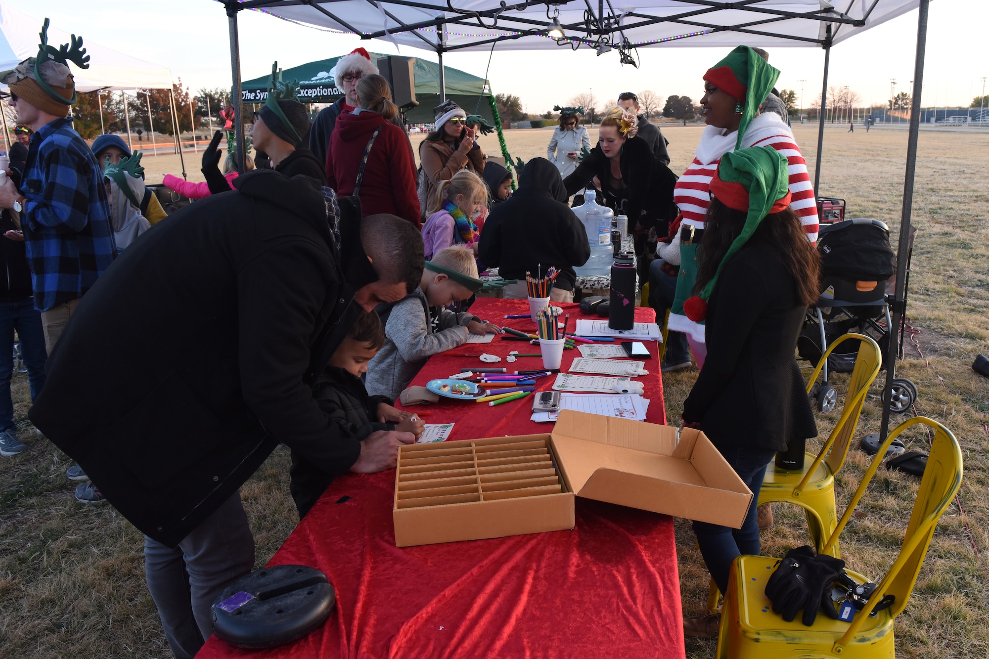A father helps his child write a letter to Santa during the Tree Lighting Ceremony at the parade field on Goodfellow Air Force Base, Texas, Dec. 4, 2018. The letters written to Santa were gathered and sent off to the North Pole with the mailbox at the event. (U.S. Air Force photo by Airman 1st Class Zachary Chapman/Released)