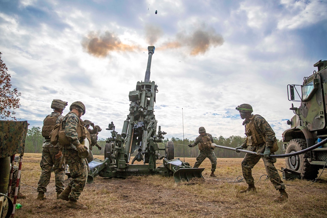 Several Marines fire an M777 howitzer.