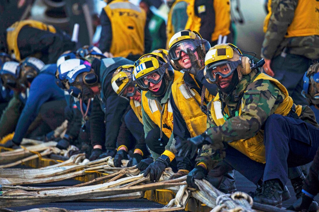 Sailors rig a barricade on a ship.