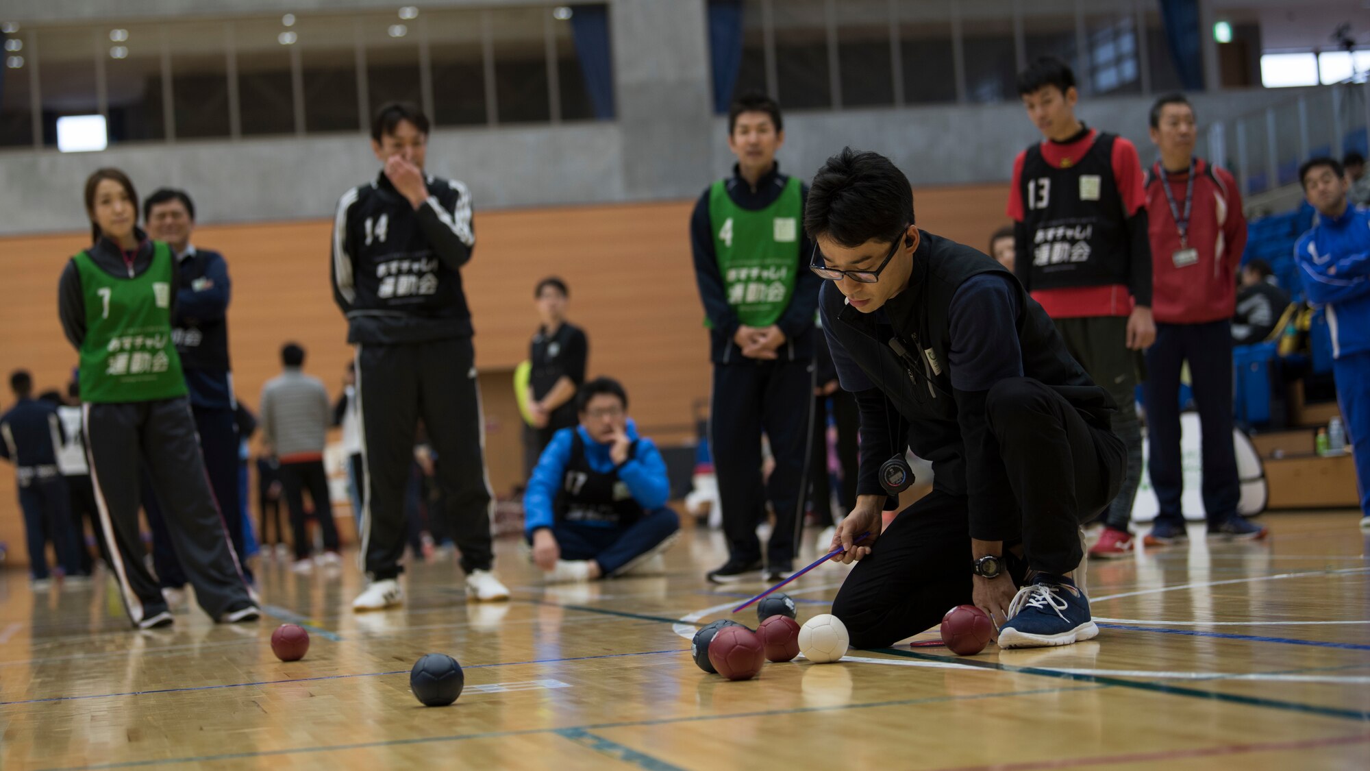 A Paralympics judge measures a hacky sack ball during a game of boccia held at the Misawa International Sports Center in Misawa City, Japan, Dec. 1, 2018. Throughout the day, attendees played goal ball and boccia, which is a tactical game comparable to shuffle board,  as well as wheelchair basketball and sitting volleyball. (U.S. Air Force photo by Airman 1st Class Collette Brooks)
