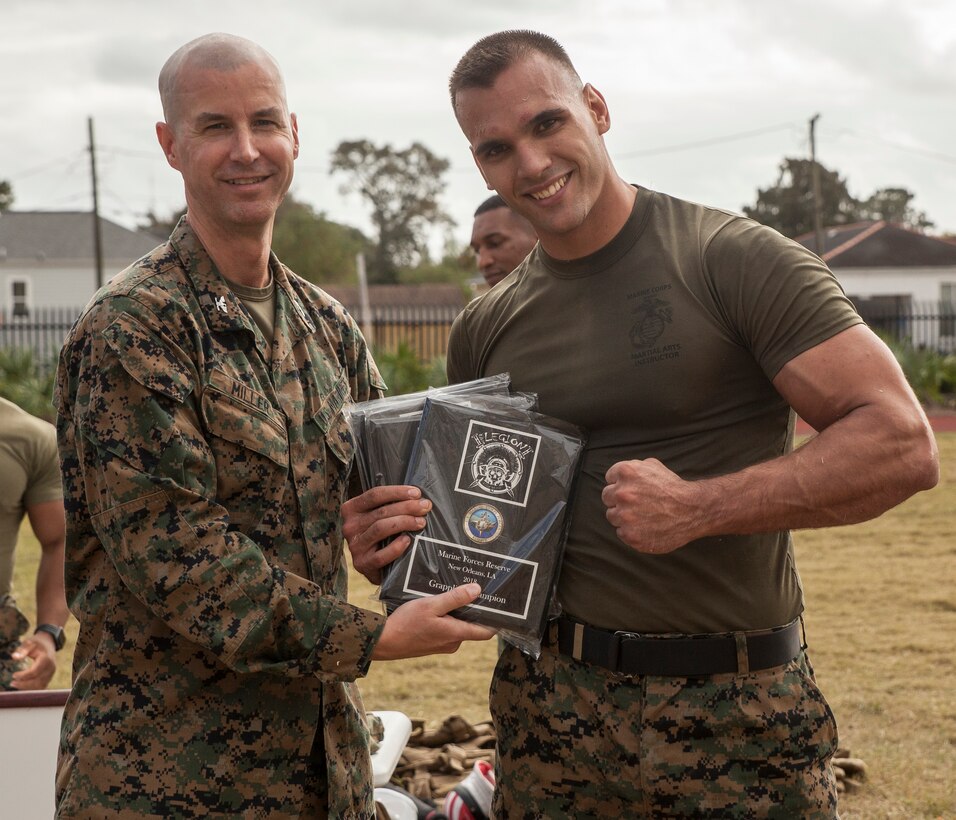 Col. Torrens G. Miller, left, commanding officer of Headquarters Battalion, Marine Forces Reserve, presents Sgt. Ian Ferro, right, training non-commissioned officer with MARFORRES S-3, the winning awards for the MFR King of the Ring tournament held at Marine Corps Support Facility New Orleans, Nov. 30, 2018. The tournament challenges competitors to three categories of knife fighting, grappling and baton fighting to become the overall King of the Ring champion. (U.S. Marine Corps photo by Sgt. Dante J. Fries)