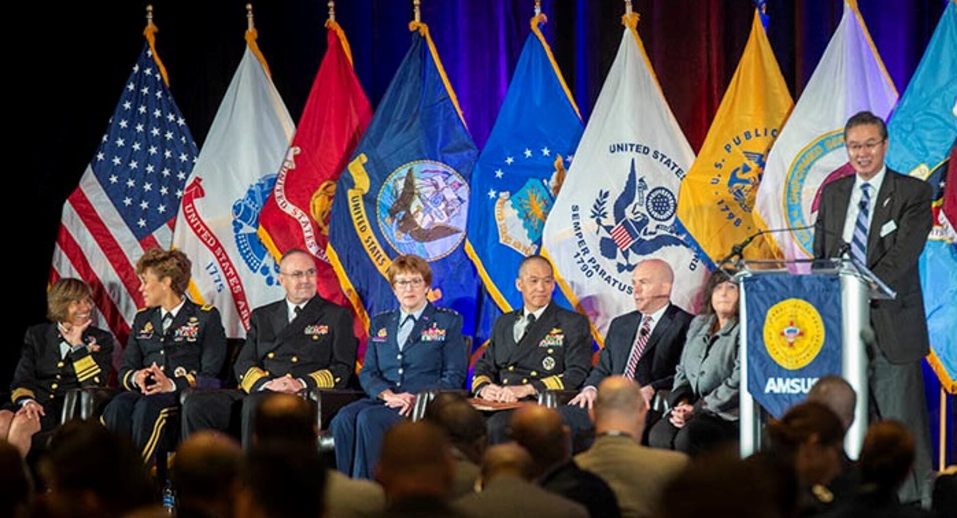 Dr. John Cho (far right), AMSUS executive director, introduces speakers (from left) Navy Vice Adm. Raquel Bono, Defense Health Agency director; Lt. Gen. Nadja West, Army Surgeon General; Vice Adm. Forrest Faison III, Navy Surgeon General; Lt. Gen. Dorothy Hogg, Air Force Surgeon General; Navy Rear Adm. Colin Chinn, Joint Staff surgeon, Dr. Richard Thomas, president of Uniformed Services University of the Health Sciences; and Dr. Terry Adirim, Deputy Assistant Secretary of Defense for Health Services Policy and Oversight.