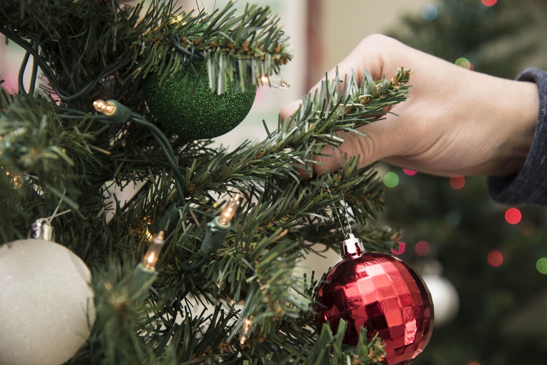 U.S. Air Force Airman 1st Class Daniel Ortiz, a 35th Civil Engineer Squadron heating, ventilation and air conditioning technician, places an ornament on a Christmas tree during the 18th Annual Holiday Lights Tour at Misawa Air Base, Japan, Dec. 16, 2017. Many Team Misawa members volunteered to deliver holiday cheer to the local community by bringing cookies, fun activities and Santa to show participants an American-style Christmas event. (U.S. Air Force photo by Senior Airman Sadie Colbert)