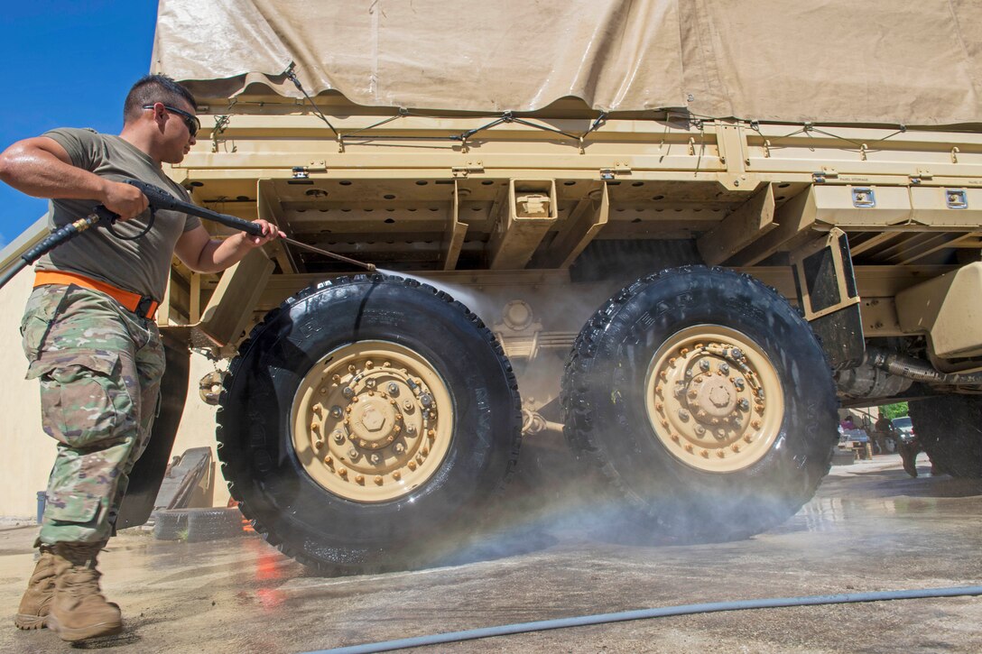 An airman washes a tactical vehicle with a hose.