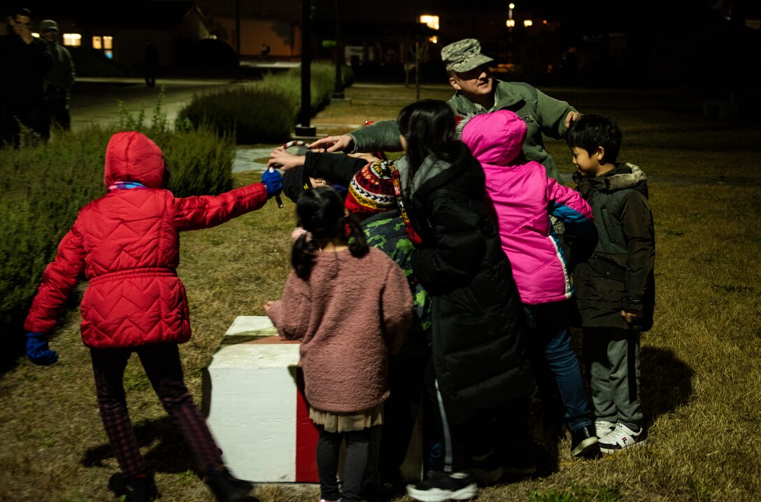 U.S. Air Force Col. John Bosone, 8th Fighter Wing commander, pulls a lever to light the base Christmas tree with Korean children at Kunsan Air Base, Republic of Korea, Nov. 29, 2018. Kunsan celebrated the start of the holiday season with a base-wide event held by the 8th FW chapel. (U.S. Air Force photo by Senior Airman Stefan Alvarez)