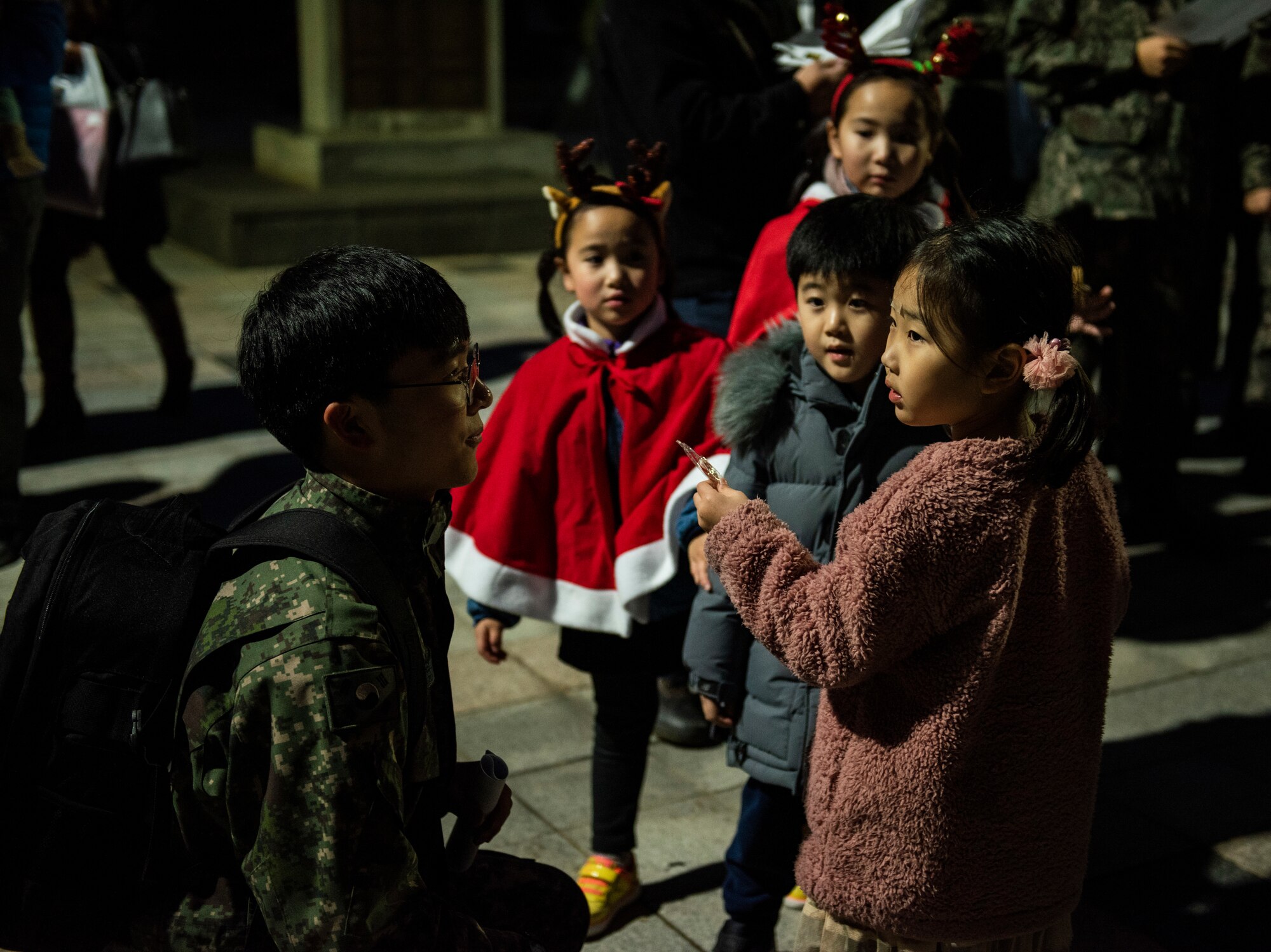 A member of the 38th Fighter Group, Republic of Korea Air Force, gives a candy cane to a child at a tree lighting ceremony at Kunsan Air Base, Republic of Korea, Nov. 29, 2018. Kunsan celebrated the start of the holiday season with a base-wide event held by the 8th FW chapel. (U.S. Air Force photo by Senior Airman Stefan Alvarez)