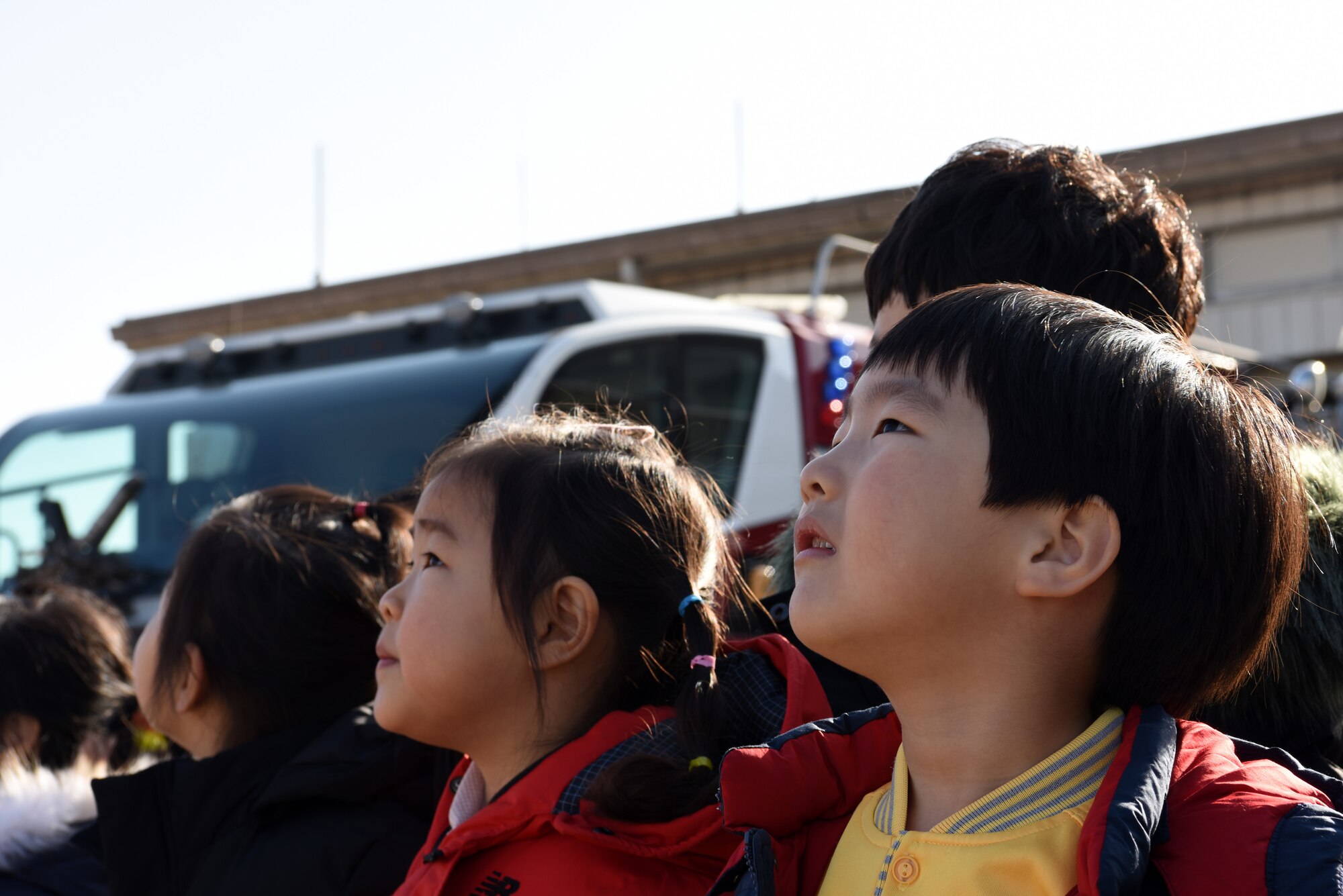 Kwon Na, Korean Christian International School student, watches as a fire truck sprays water into the air at Kunsan Air Base, Republic of Korea, Nov. 30, 2018. The students visited the 8th Civil Engineer Squadron to tour the fire station and learn more about being a firefighter. (U.S. Air Force photo by Staff Sgt. Joshua Edwards)