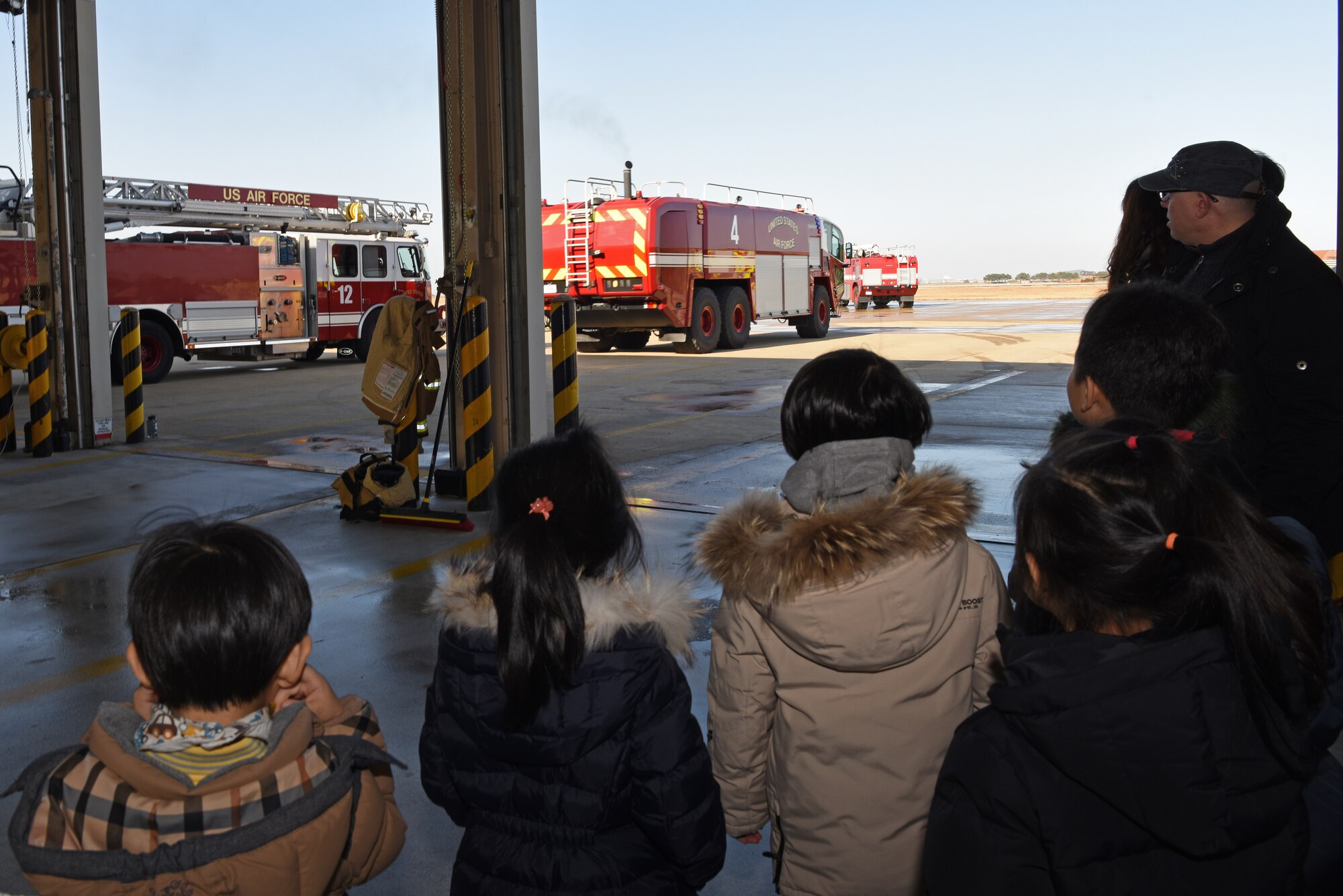 Korean Christian International School students and teachers watch 8th Civil Engineer Squadron firefighters respond to a call at Kunsan Air Base, Republic of Korea, Nov. 30, 2018. The firefighters reacted when called to assist an F-16 Fighting Falcon that needed emergency repairs. (U.S. Air Force photo by Staff Sgt. Joshua Edwards)