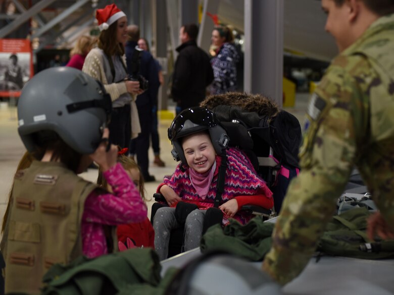 Guests of the492nd Fighter Squadron Christmas Party try on pilot’s helmets and gear at the Duxford Imperial War Museum, Cambridge, England, Dec. 1, 2018. Around 50 members and spouses from the 492nd FS ‘Madhatters’ collaborated with the three charity organizations to help bring some extra joy this holiday season to children with serious or terminal illness or severe burns. (U.S. Air Force photo by Staff Sgt. Alex Fox Echols III)