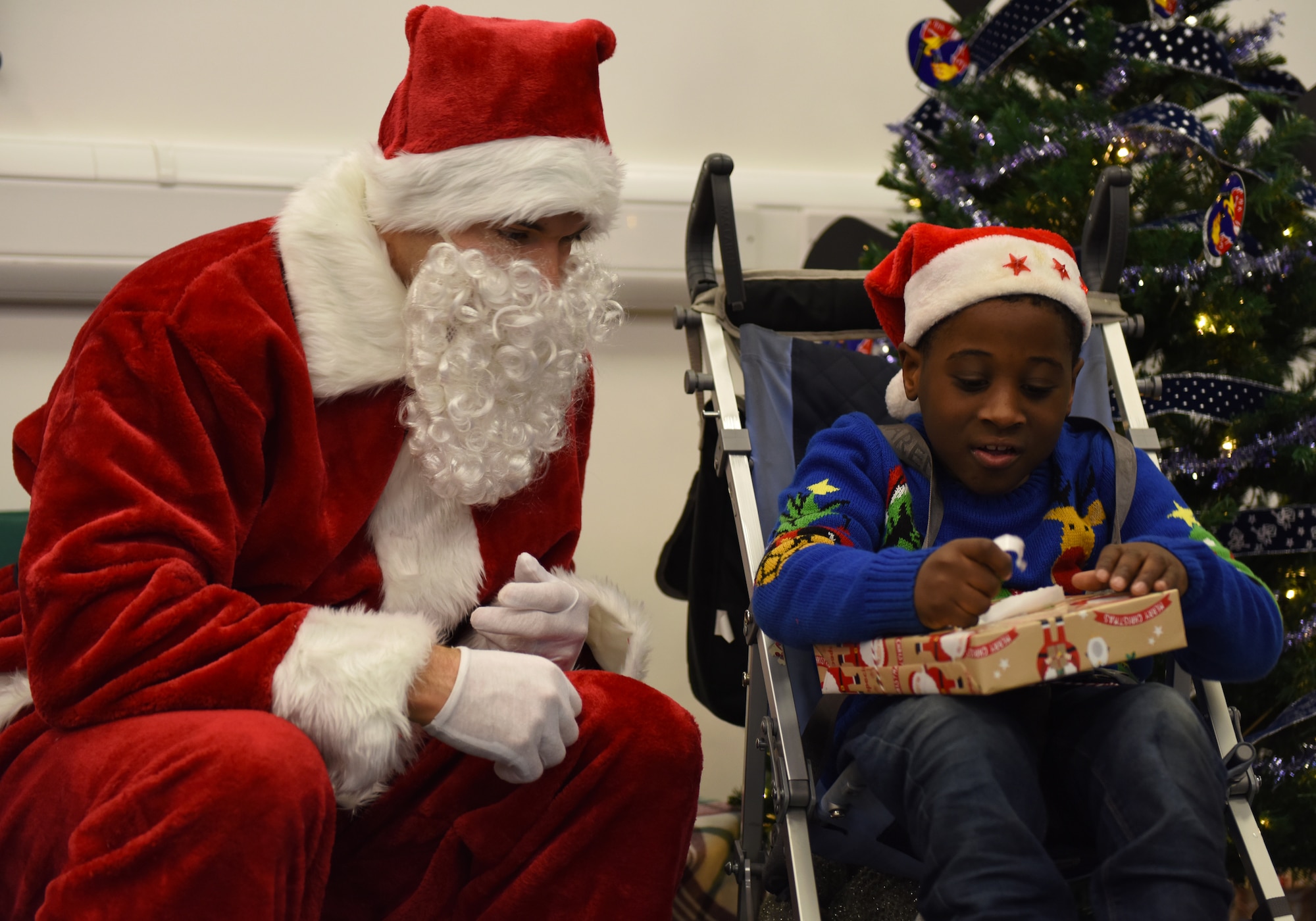 A guest of the 492nd Fighter Squadron Children’s Christmas Party receives a present from Santa Clause at the Duxford Imperial War Museum, Cambridge, England, Dec. 1, 2018. More than 100 children enjoyed carnival games, festive arts and crafts, pilot equipment displays, Morse code lessons, and a special visit and presents from Father Christmas himself. (U.S. Air Force photo by Staff Sgt. Alex Fox Echols III)