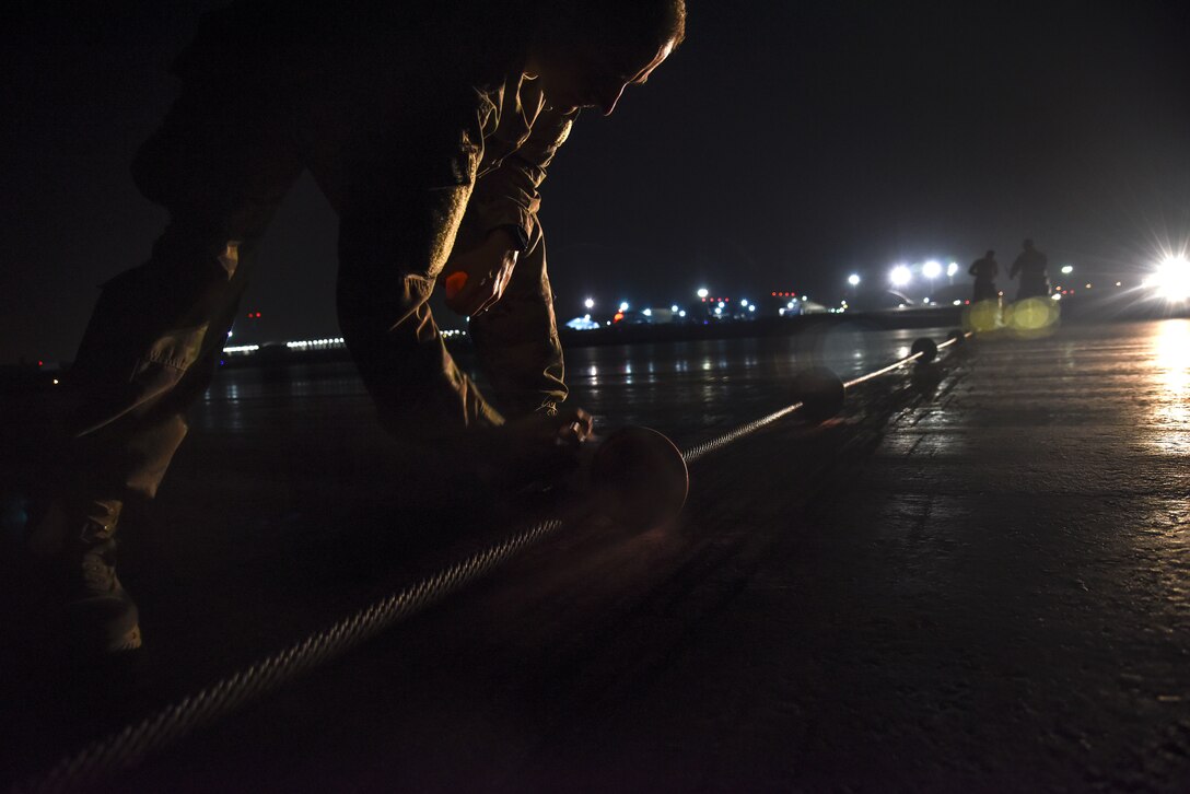 U.S. Air Force Staff Sgt. Elisha O’Leske, 380th Expeditionary Civil Engineer Squadron electrical power production and barrier maintenance craftsman, sprays red paint on the centerline donut of a BAK-12 Aircraft Arresting System at Al Dhafra Air Base, United Arab Emirates, Nov. 24, 2018. The Power Production barrier maintenance shop’s job centers on a 195-foot-long cable that assists in the case of a fighter jet in need of an emergency landing at ADAB. (U.S. Air Force photo by Senior Airman Mya M. Crosby)