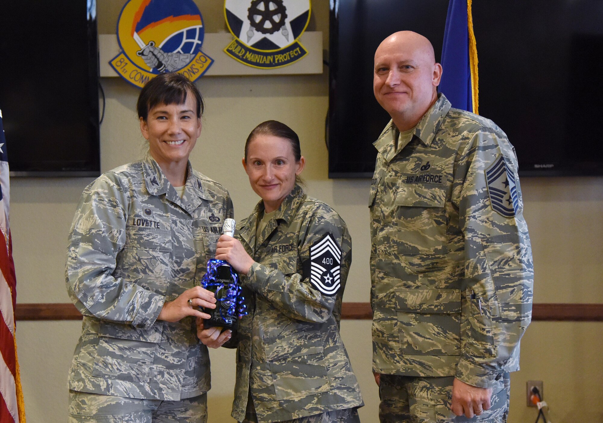 U.S. Air Force Col. Debra Lovette, 81st Training Wing commander, and Chief Master Sgt. David Pizzuto, 81st TRW command chief, present Senior Master Sgt. Katie Hammonds, 81st Medical Support Squadron medical logistics flight chief, with a memento for her promotion to the rank of chief master sergeant at Keesler Air Force Base, Mississippi, Dec. 6, 2018. Five senior master sgts. at Keesler were selected for promotion. (U.S. Air Force photo by Kemberly Groue)